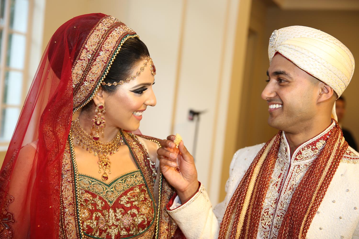 Wedding Photography of Bride and Groom feeding each other at their Asian Wedding by MAKSAM Photography London